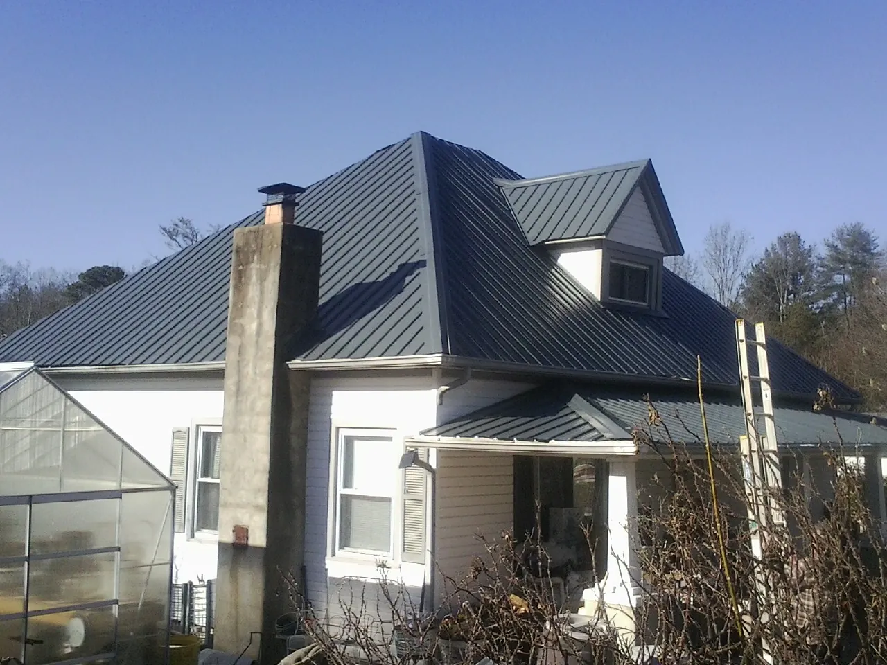 Dark blue standing seam metal roof on a white farmhouse with dormer — Slate & Tile Roof Repair by Roofing Brothers in Amesbury