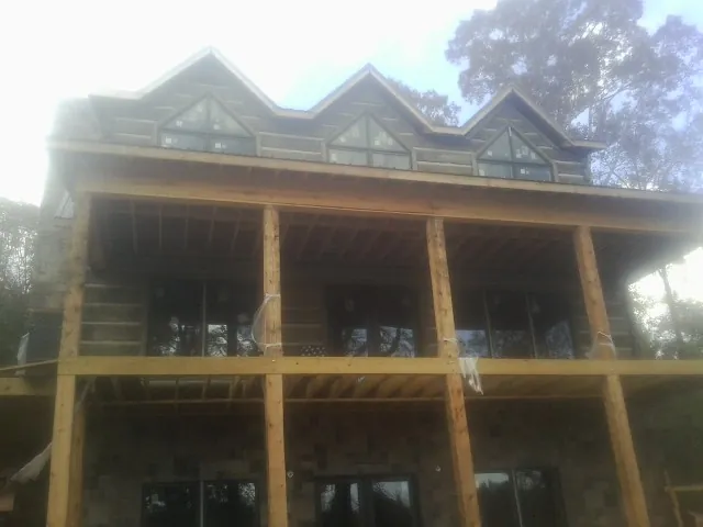 Dormers and porch framing on a large log home under construction — Roof Coating work by our crew in Amesbury