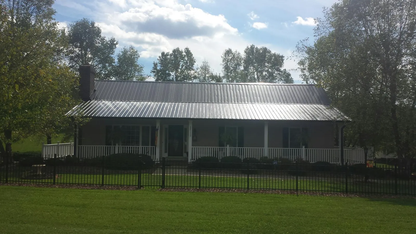 Gray metal roof on a brick ranch with a full width front porch — Gutter Guard Installation work by our crew in Amesbury