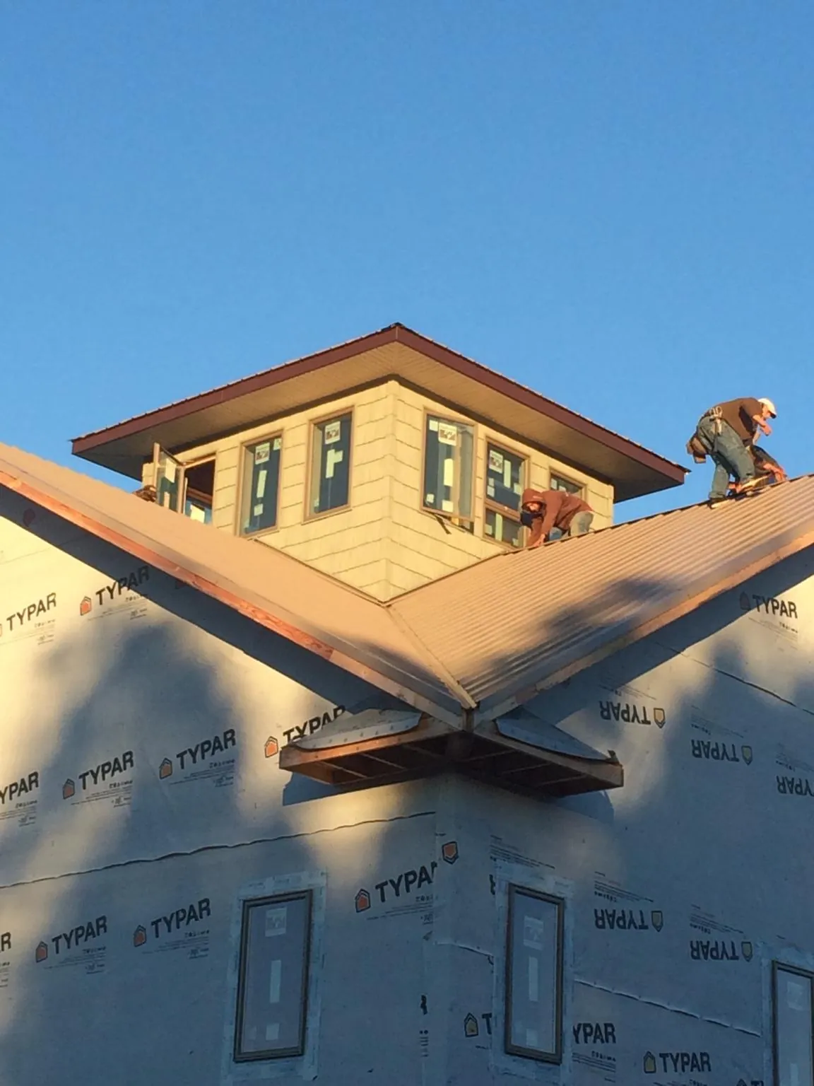 Roofers working around a rooftop cupola on a new metal roof at sunset — Roof Waterproofing in Amesbury by Roofing Brothers